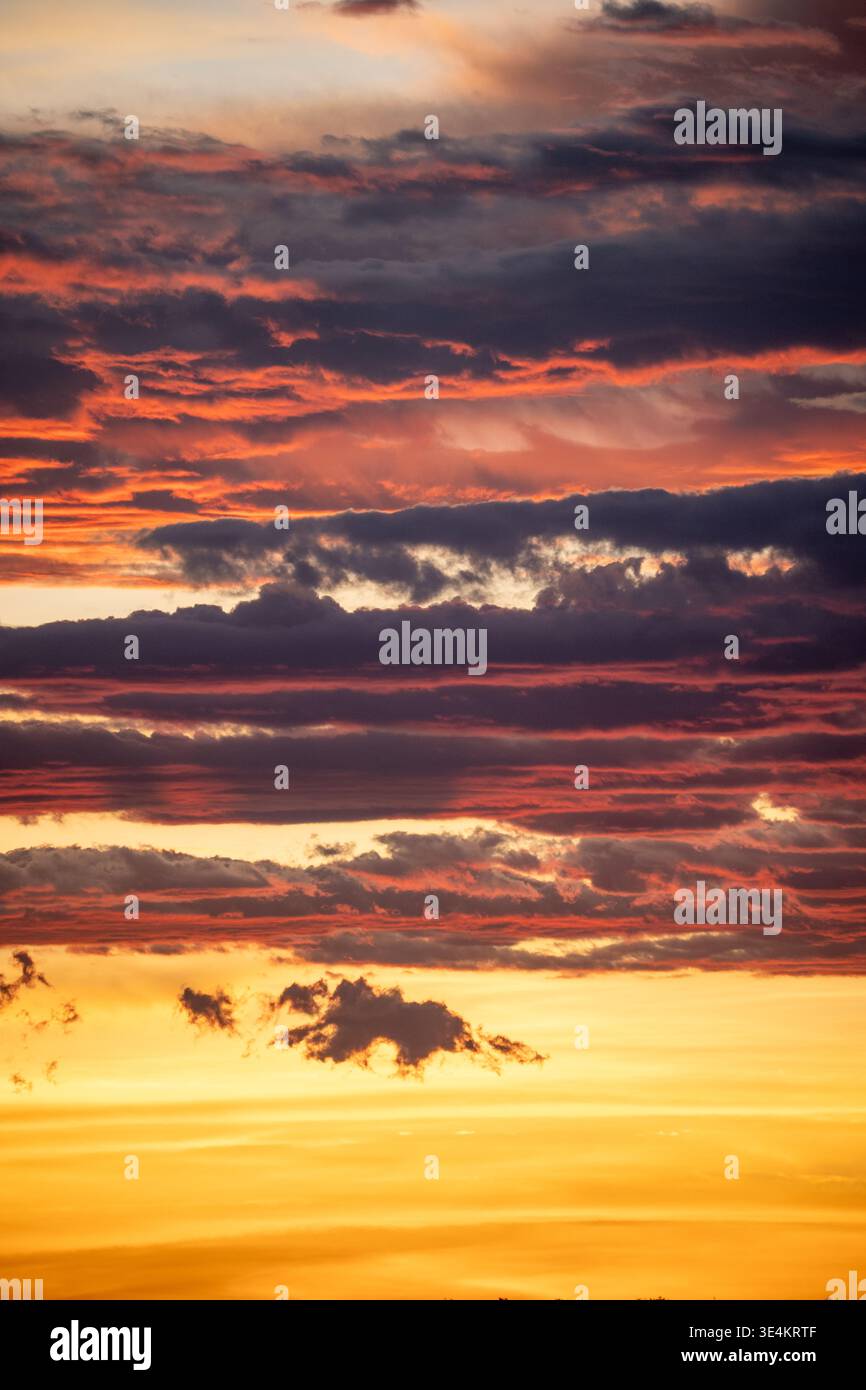 Spettacolari nuvole di tramonto su orizzonte, tonalità oro e cremisi a strati, bande di cloud testurizzato che creano cinema Foto Stock
