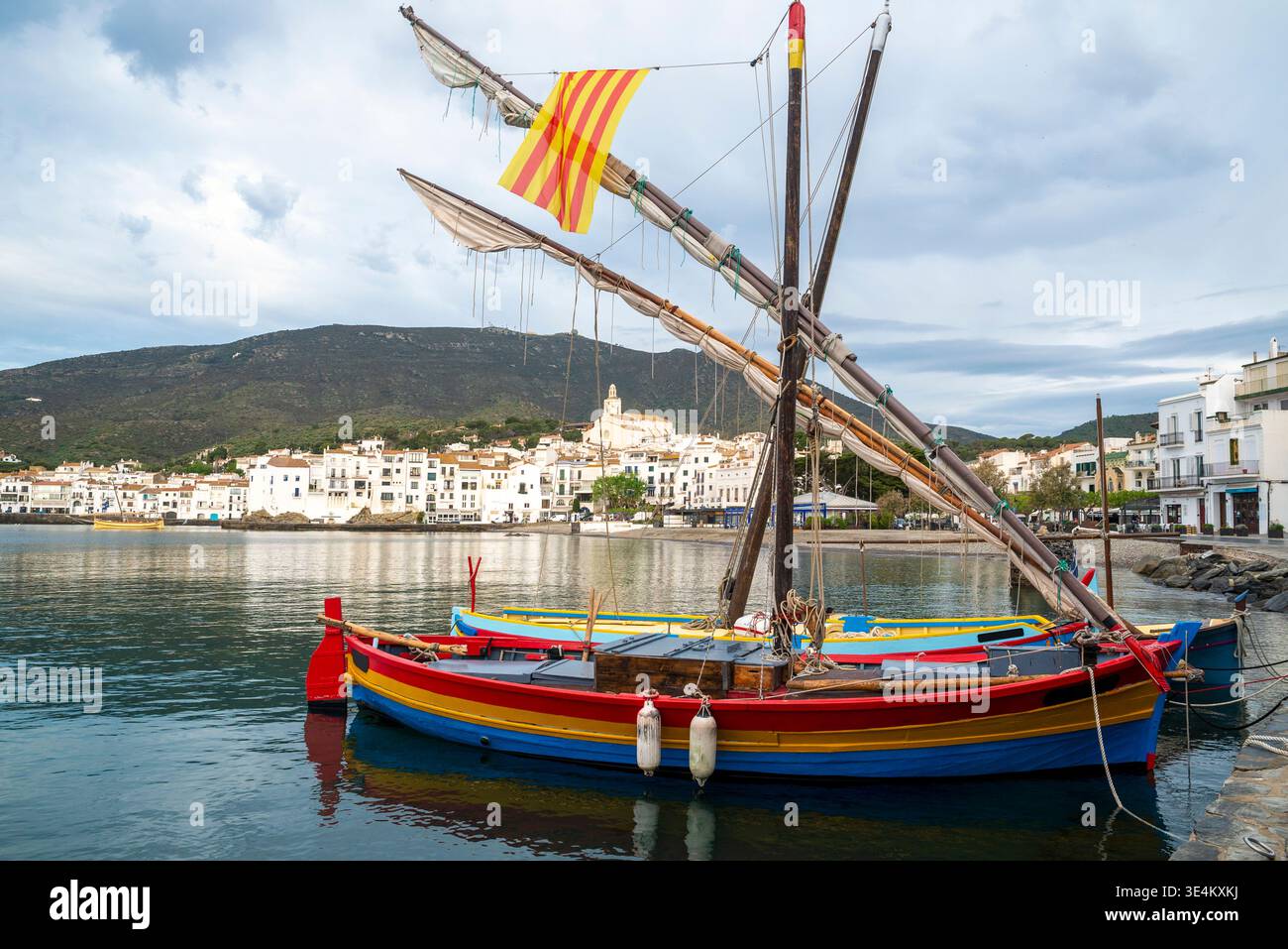 Barche da pesca colorate tradizionali ormeggiate nel porto con il paesaggio costiero di Cadaques, Girona, Catalogna, Spagna Foto Stock