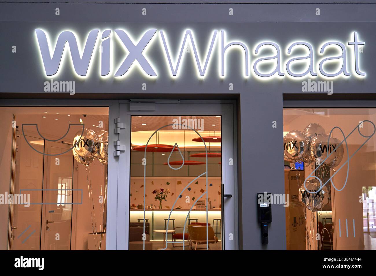 L'immagine mostra l'ingresso esterno di un ufficio Wix con segnaletica illuminata in primo piano con il testo "Wix Whaaat" montato sopra Foto Stock