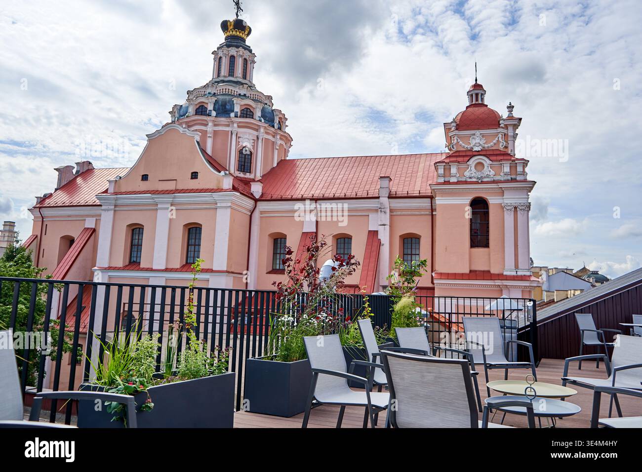 Una vista panoramica di una storica chiesa barocca con una caratteristica facciata rosa e tegole rosse, caratterizzata da una cupola ornata sormontata da una corona dorata e. Foto Stock