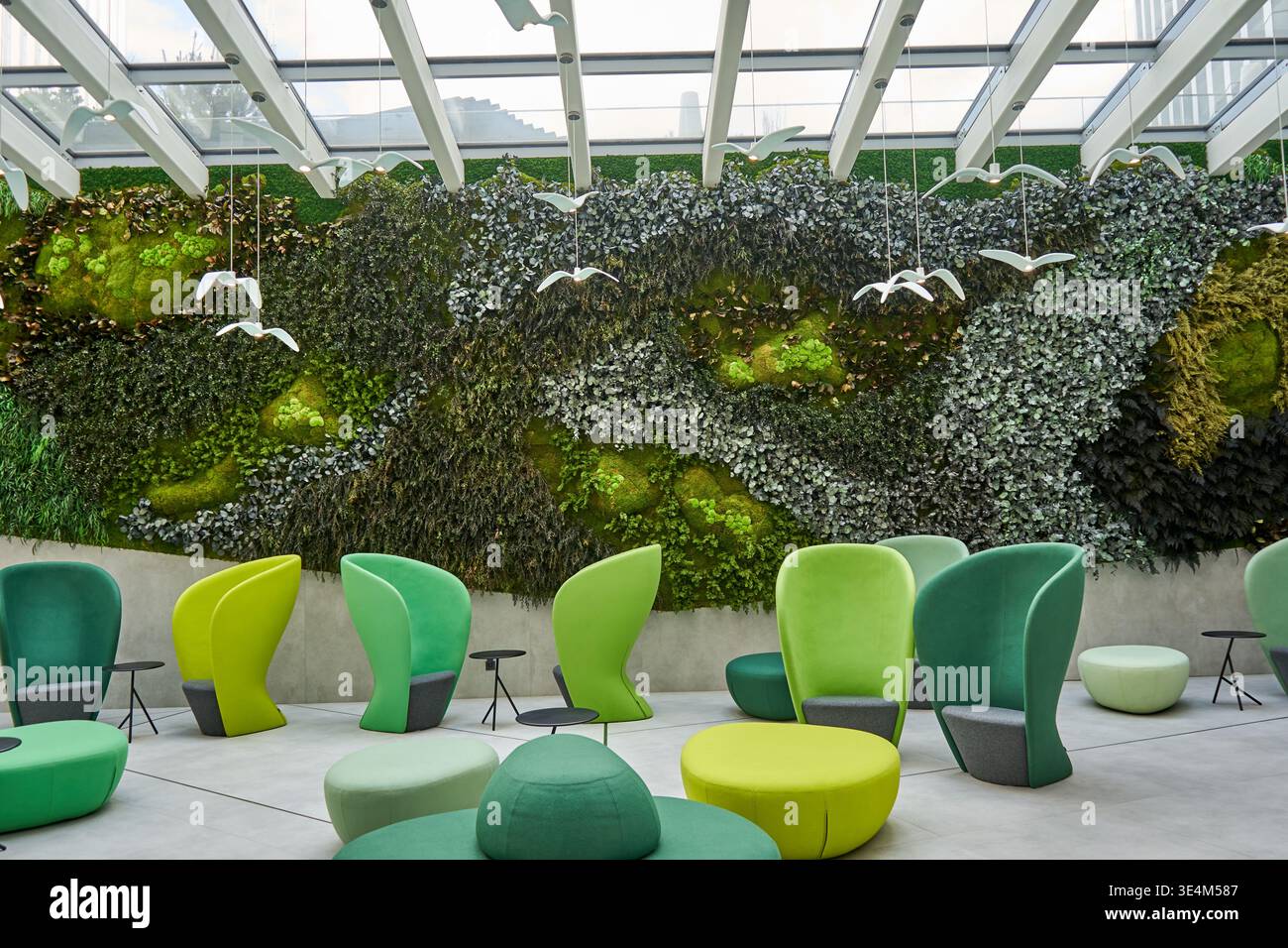 Un atrio interno moderno o un'area lounge caratterizzata da una suggestiva parete verde dal pavimento al soffitto ricoperta da vari muschi, felci e ringhiere Foto Stock