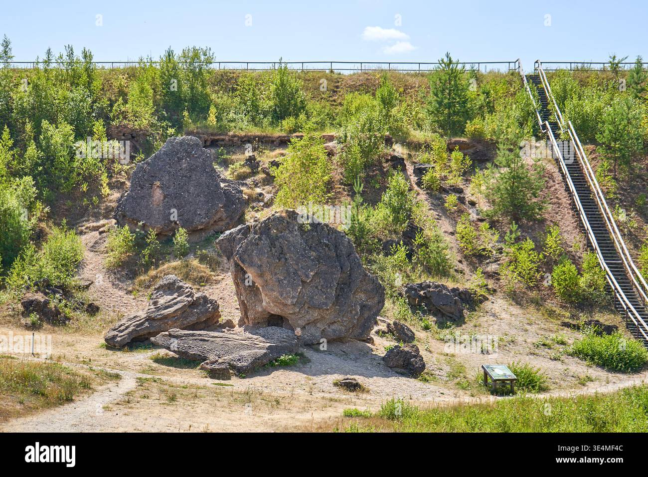 Un paesaggio naturale caratterizzato da grandi massi di granito sparsi su una collina sabbiosa. Il terreno mostra formazioni rocciose esposte e terreno eroso Foto Stock