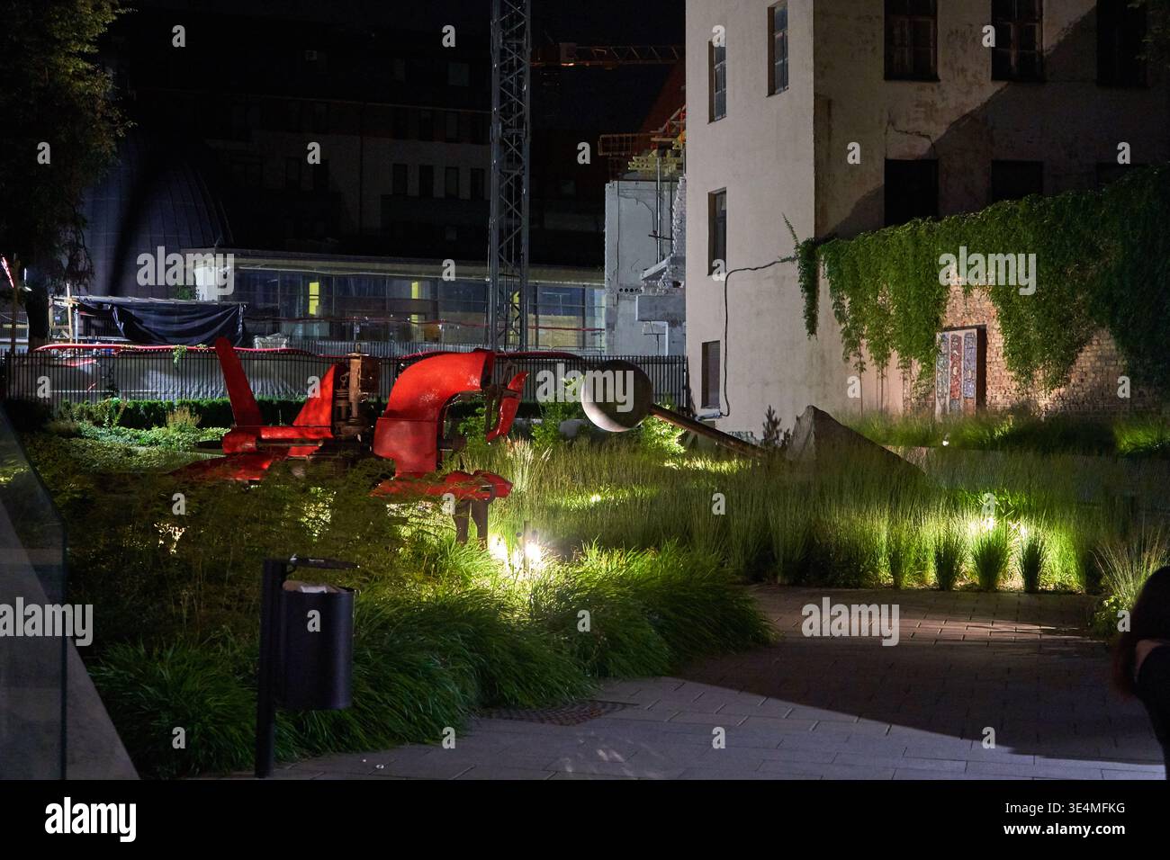 Una fotografia notturna di un'installazione di arte contemporanea all'aperto situata in un giardino urbano. La messa a fuoco centrale è caratterizzata da un grande astratto Foto Stock