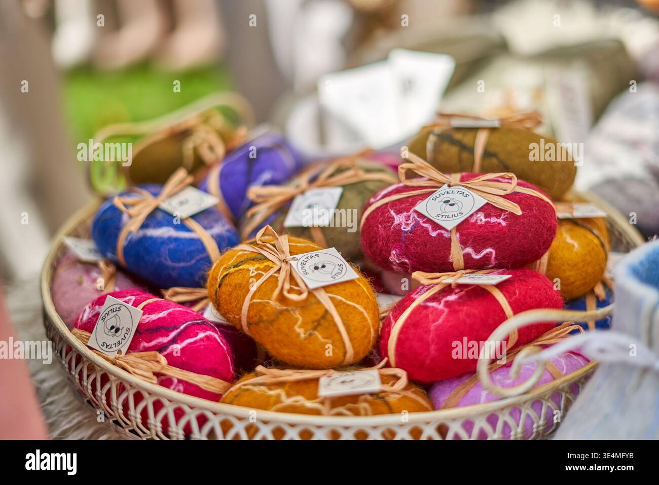 Una fotografia ravvicinata di un cesto di vimini bianco pieno di saponi colorati fatti a mano esposti in quello che sembra essere un mercato di artigianato all'aperto. Foto Stock