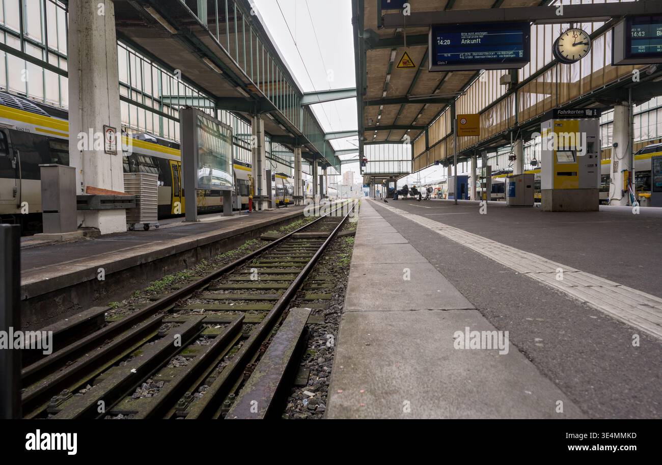 Piattaforma ferroviaria con binari, un orologio e una biglietteria in un ambiente urbano, formando una scena di trasporto pubblico strutturata. Foto Stock