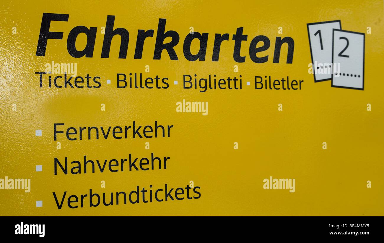 Cartello giallo che mostra le informazioni sui biglietti in più lingue, fornendo indicazioni per i passeggeri in un ambiente di trasporto pubblico. Foto Stock