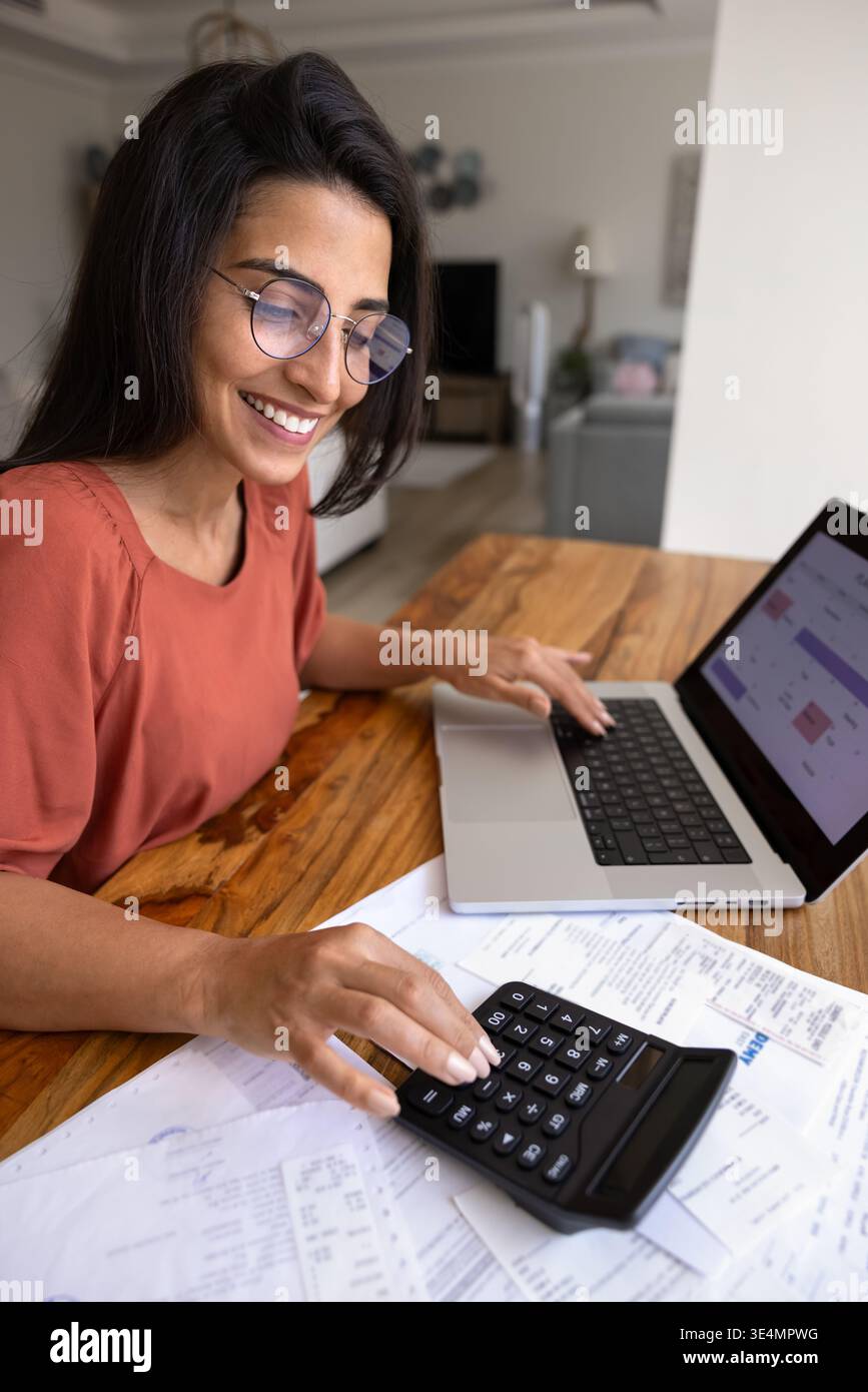 Donna brasiliana sorridente che gestisce il suo budget casalingo Foto Stock