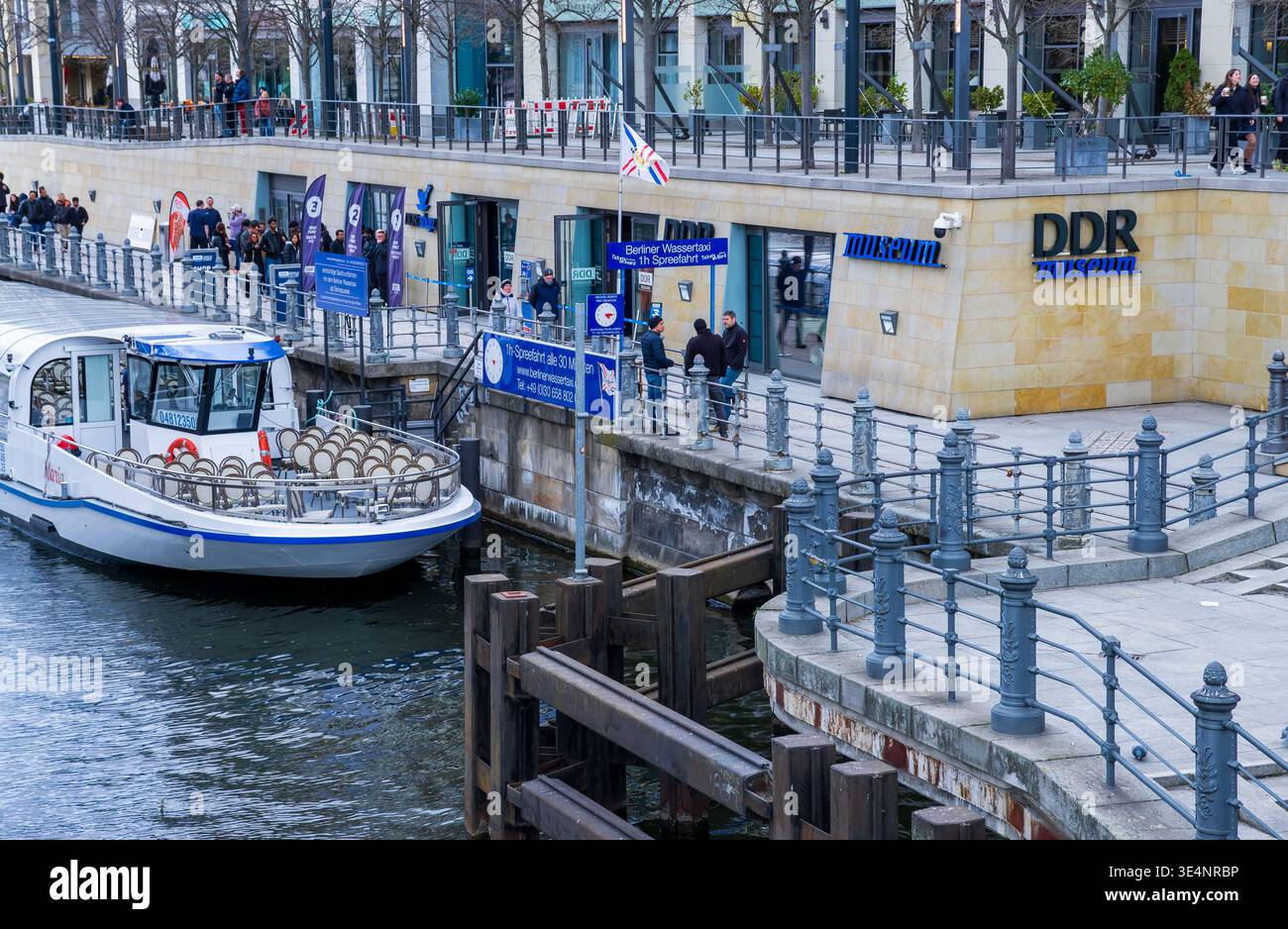I visitatori che aspettano fuori dal DDR Museum di Berlino vicino al fiume Sprea, fotografati dal ponte Liebknecht nel centro di Berlino, Germania. Foto Stock