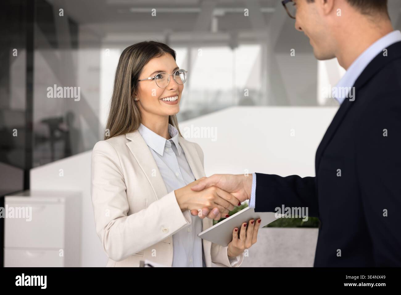 Una donna professionale stringe la mano a un collega o a un cliente maschio Foto Stock