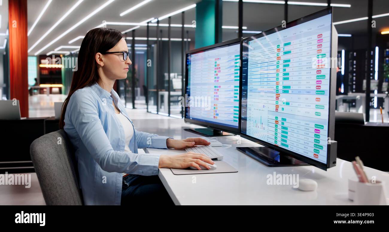 Donna che esamina attentamente i codici di fatturazione medica sullo schermo del computer dell'ufficio Foto Stock