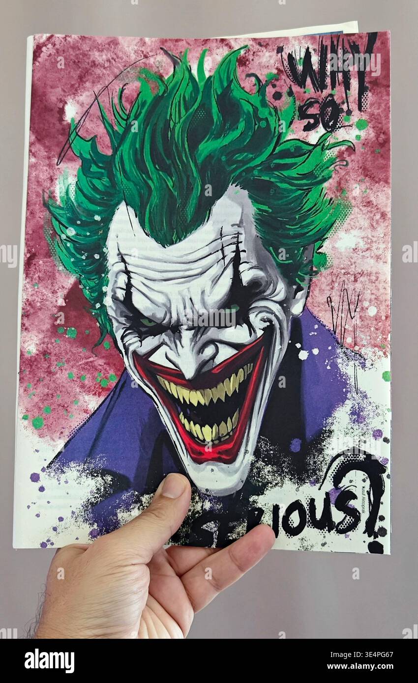 Mano che regge una rivista turca con un'illustrazione stilizzata e ad alto contrasto del Joker con i capelli verdi e il "perché così serio?" citazione. Foto Stock