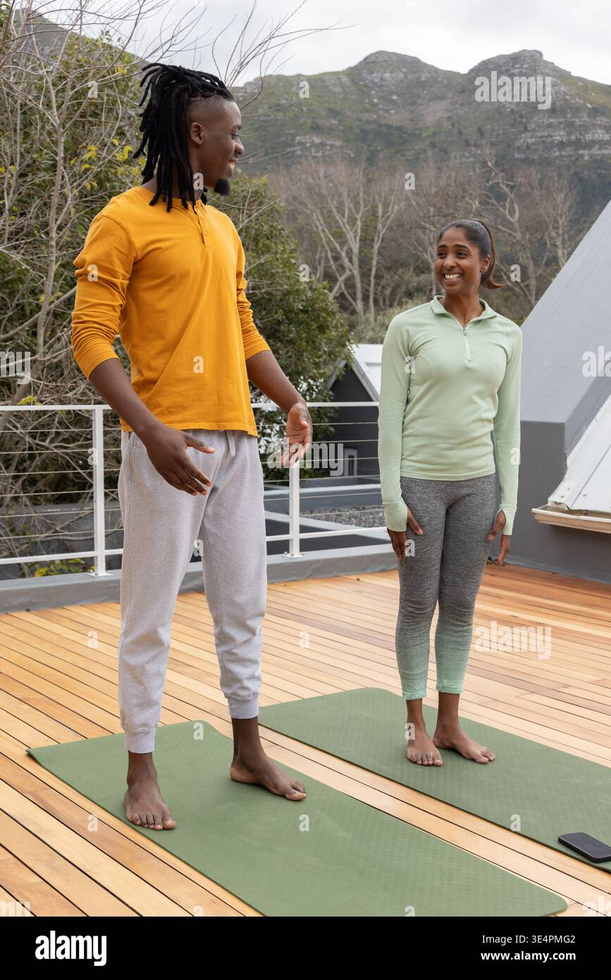 Diversi partner di allenamento che fanno yoga con abbigliamento sportivo su uno smartphone con tappetini verdi sul tetto vicino al tappetino destro Foto Stock