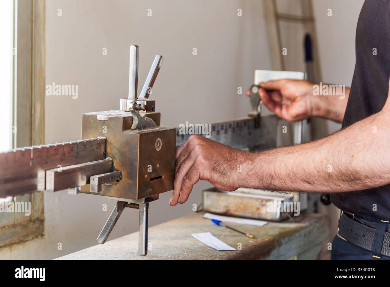 Uomo che utilizza bilance industriali per la regolazione dei pesi scorrevoli Foto Stock