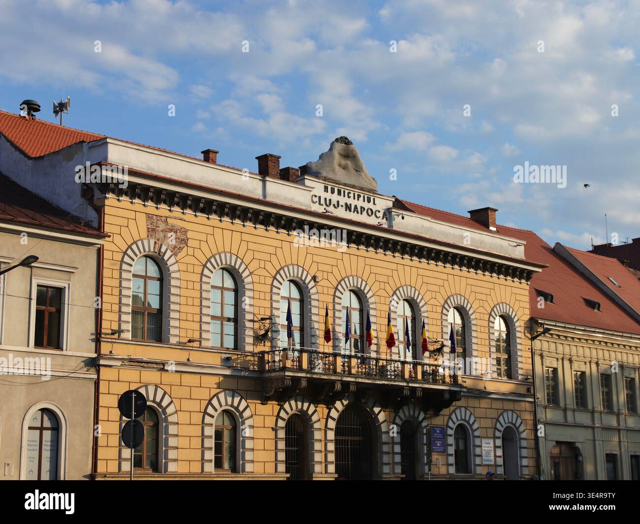 Cluj-Napoca, Romania - 12 agosto 2025: Edificio municipale di Cluj-Napoca con bandiere rumene nel centro storico Foto Stock