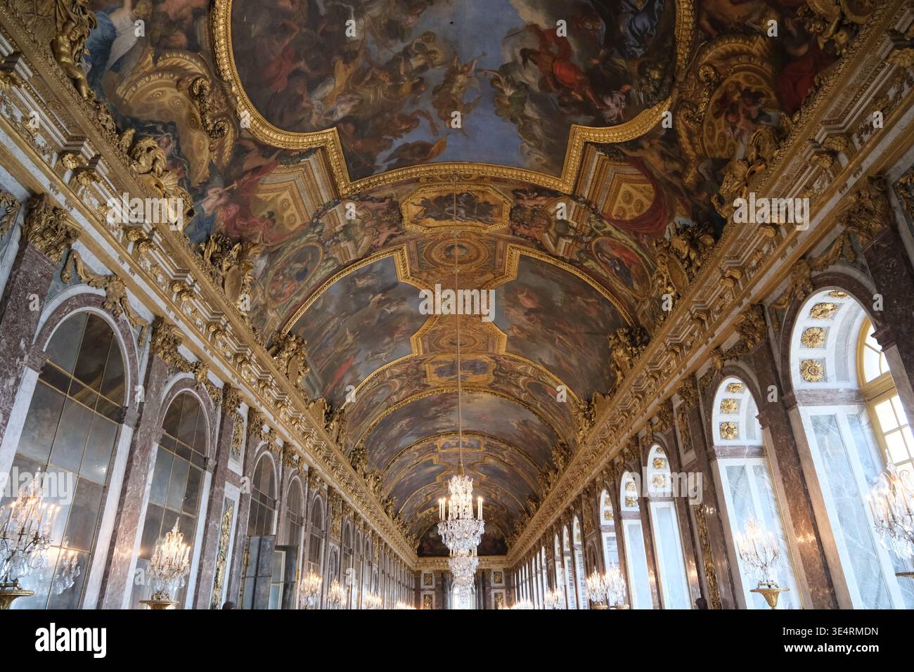 Parigi, Francia-4 ottobre 2025: Dipinti ornati sul soffitto, lampadari e galleria a specchio nella sala degli specchi della Reggia di Versailles Foto Stock
