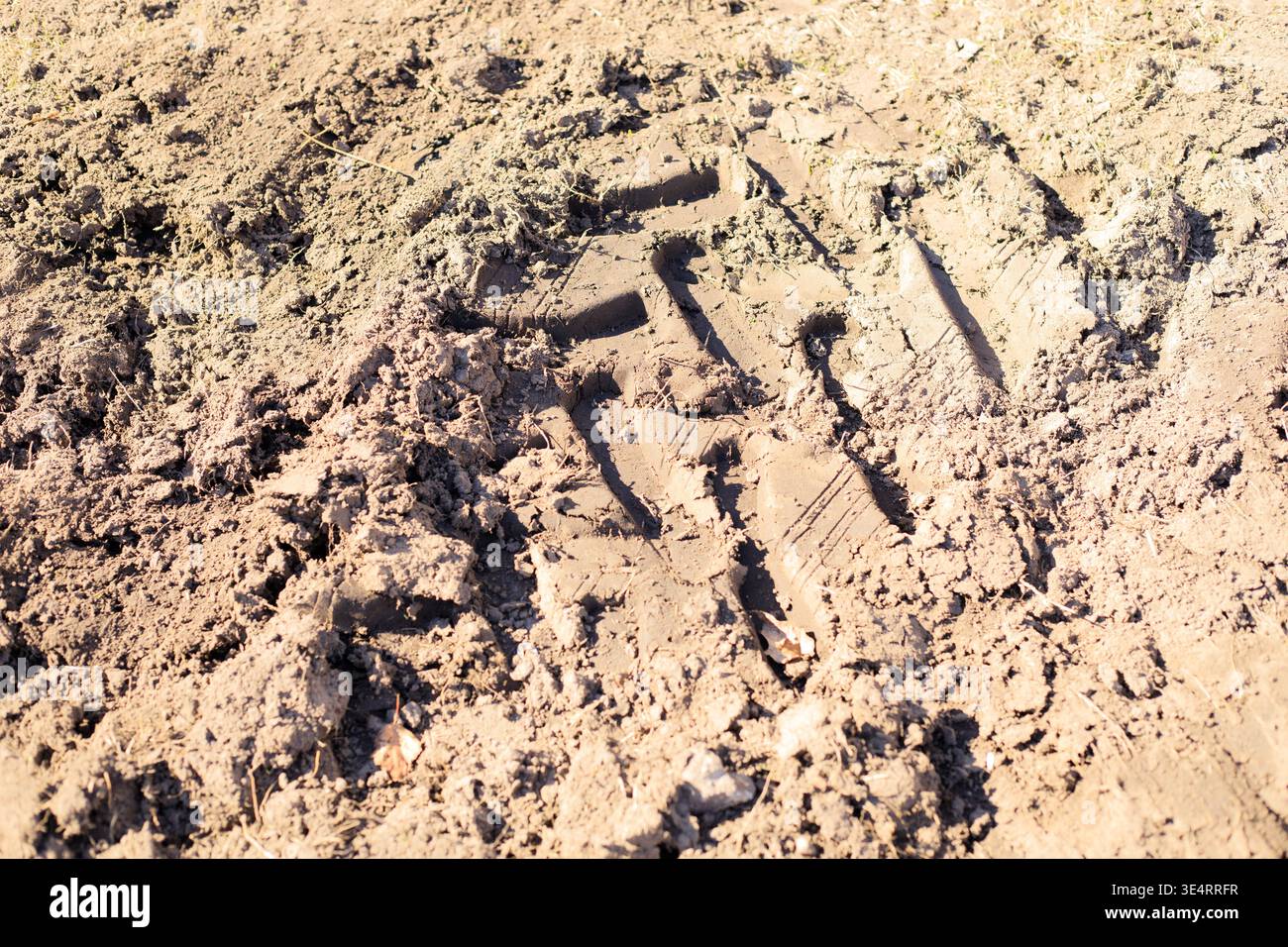 Segni di trazione provenienti dal trattore e dalle attrezzature da cantiere su terreno sabbioso bagnato. Impatto del traffico di veicoli fuoristrada e dell'attività umana sulla superficie del suolo. Foto Stock