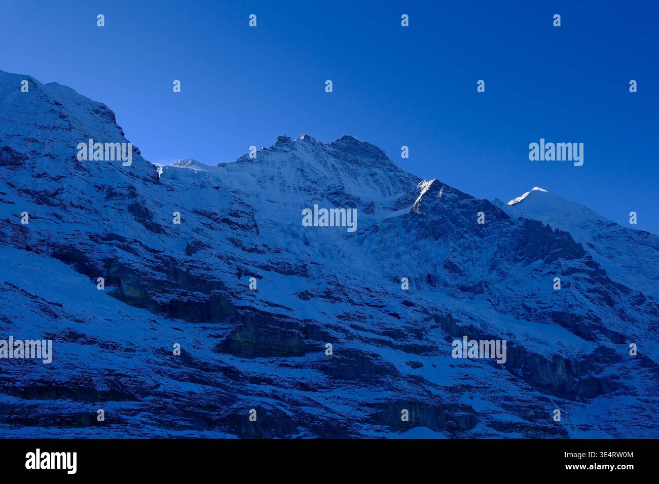 Maestosa vista invernale della parete nord dell'Eiger nelle Alpi svizzere sotto un cielo blu profondo in Svizzera Foto Stock
