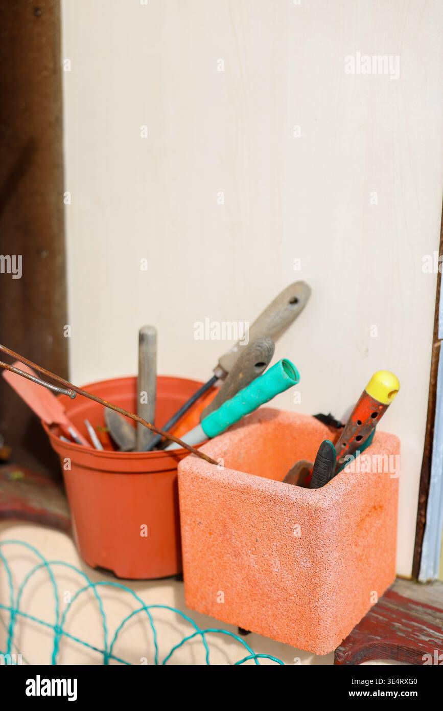 Utensili da giardinaggio in vasi vicino alla parete, attrezzature da giardino domestiche, lavori in cortile primaverile e manutenzione fai da te all'aperto. Foto Stock