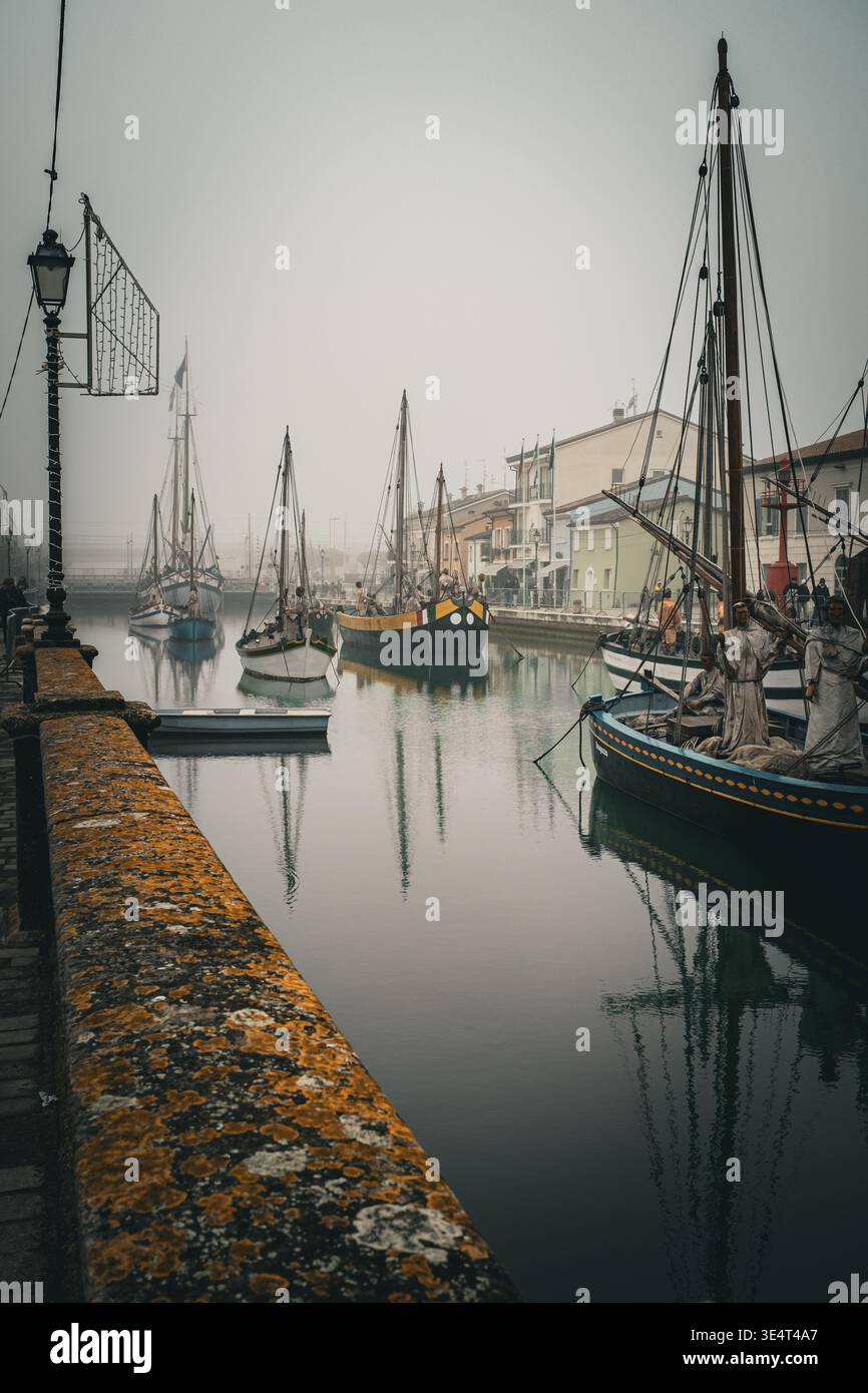 Barche da pesca tradizionali ormeggiate nel porto del canale nebbioso di Cesenatico, in Italia, durante l'inverno Foto Stock