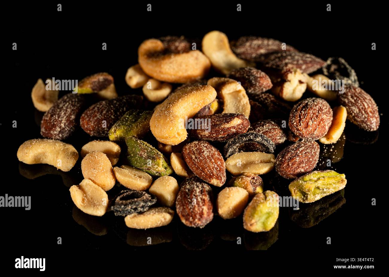Primo piano di frutta a guscio mista e frutta secca sparsi su sfondo nero. Concetto di snack salutari, cibo naturale, spazio copia. Foto Stock