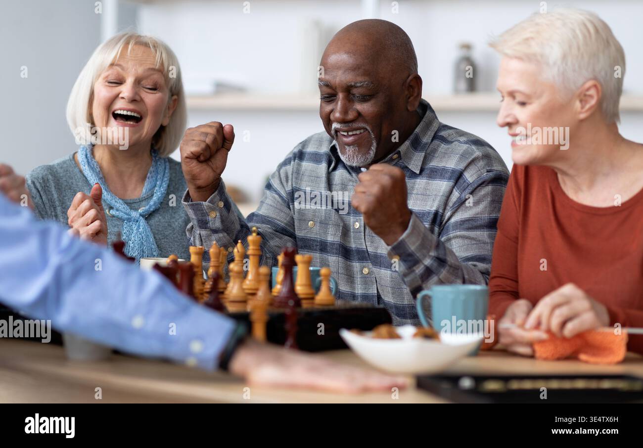 Emotivo uomo nero che gioca a scacchi con amici multirazziali Foto Stock