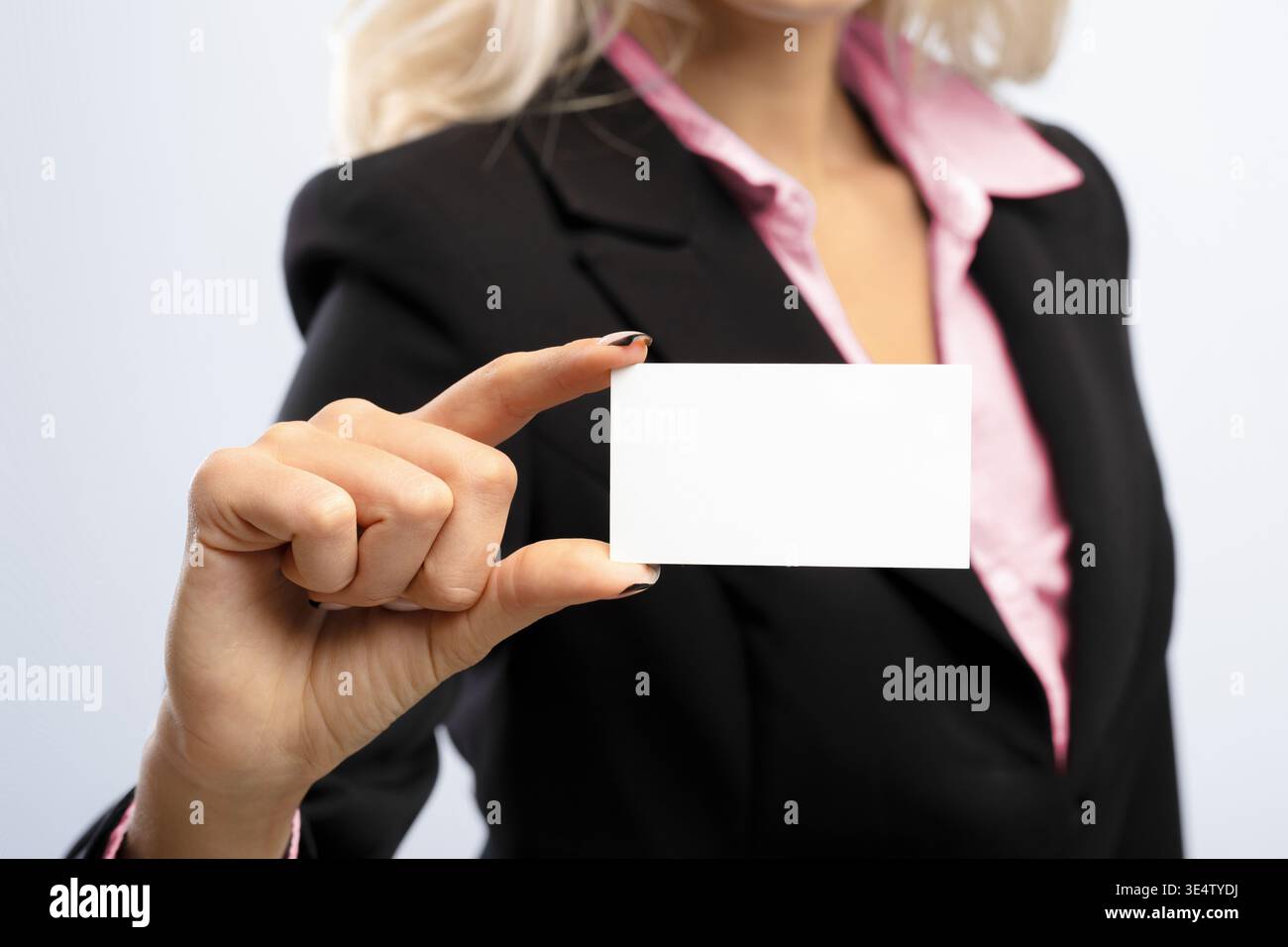 Una donna d'affari tiene una carta vuota nell'ambiente ufficio con sfondo neutro per scopi di branding Foto Stock