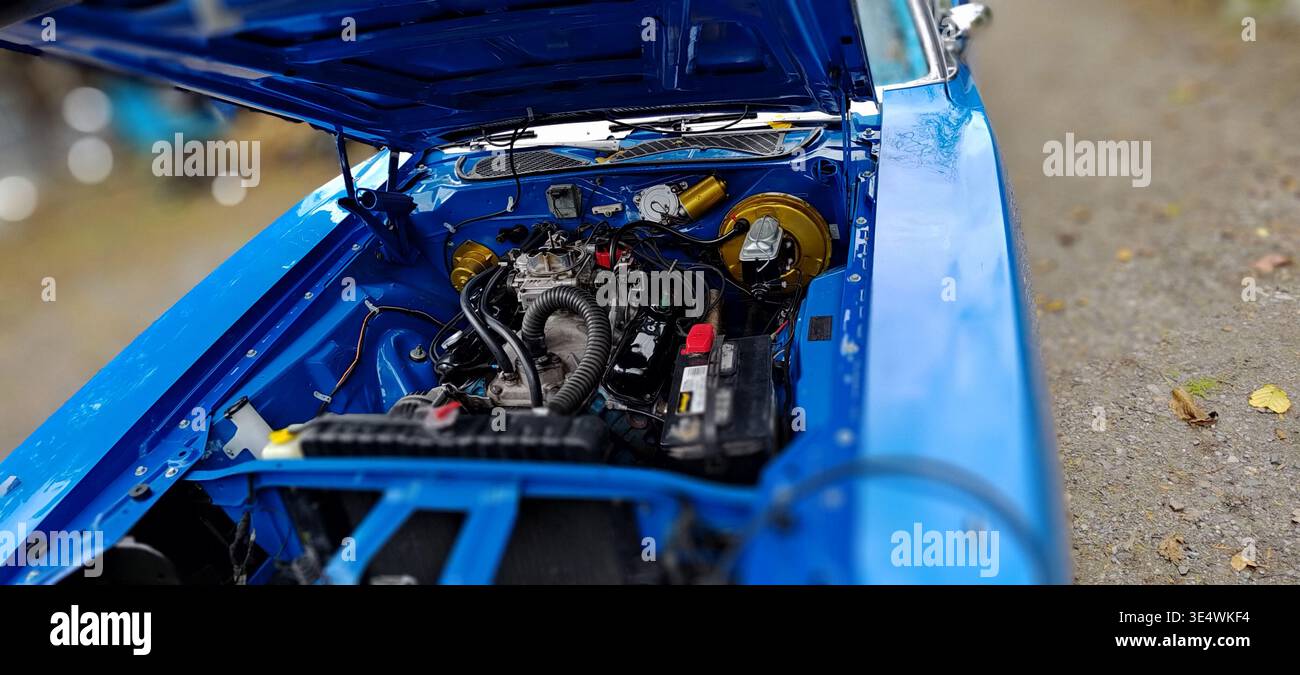 Classica auto americana con cofano aperto che mostra il vano motore, la carrozzeria blu e i componenti meccanici, parte di una serie di dettagli di un veicolo vintage. Foto Stock