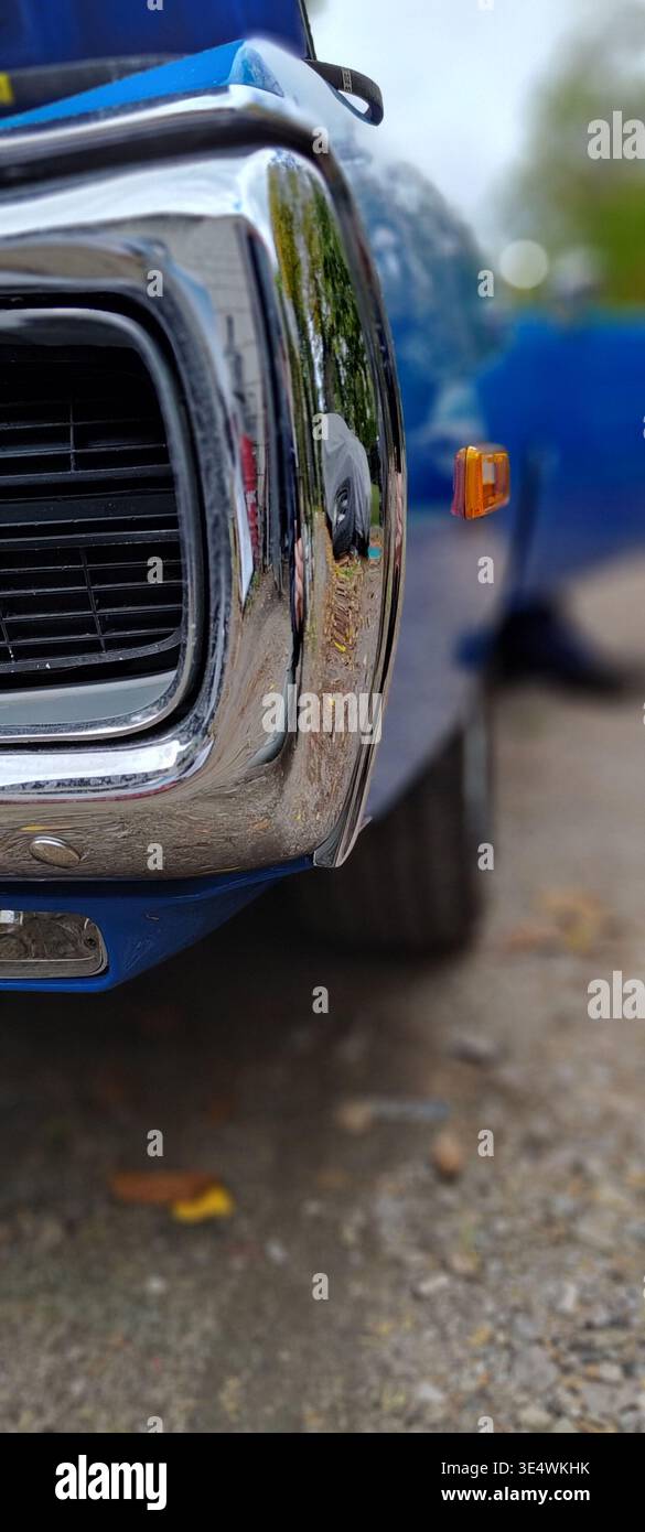 Primo piano della griglia anteriore e del paraurti cromato di una classica auto americana, carrozzeria blu con riflessi, parte di una serie di dettagli di un veicolo vintage. Foto Stock