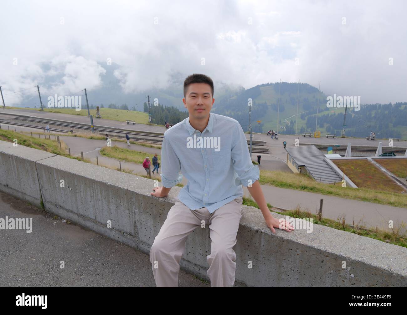 Giovane asiatico seduto sulla cima del Monte Rigi, Svizzera Foto Stock