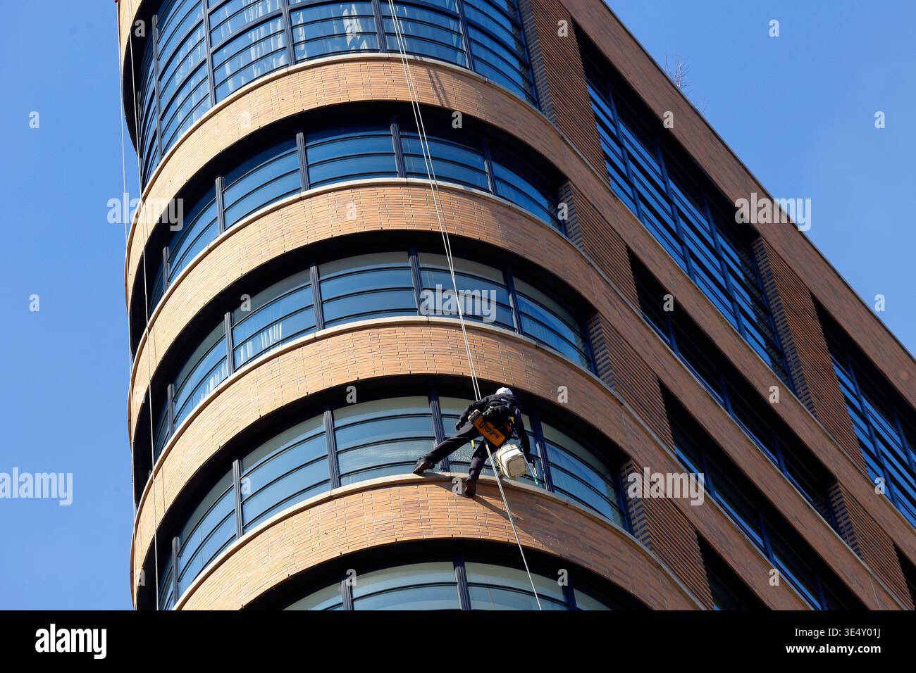 Una lavavetri seduta in una sedia a sdraio pulisce una finestra di un edificio residenziale a New York City Foto Stock