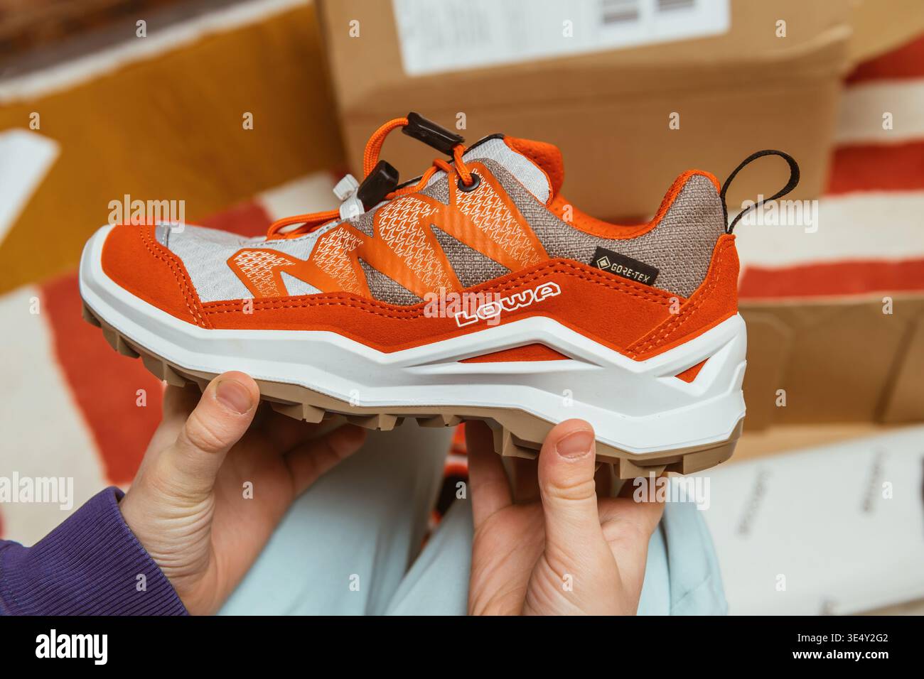 Parigi, Francia - 12 marzo 2026: Primo piano di padre e figlio che tengono in mano la scarpa da trekking Lowa durante l'unboxing a casa, mettendo in evidenza il design delle calzature per esterni il comfort e la tecnologia impermeabile Gore Tex Foto Stock