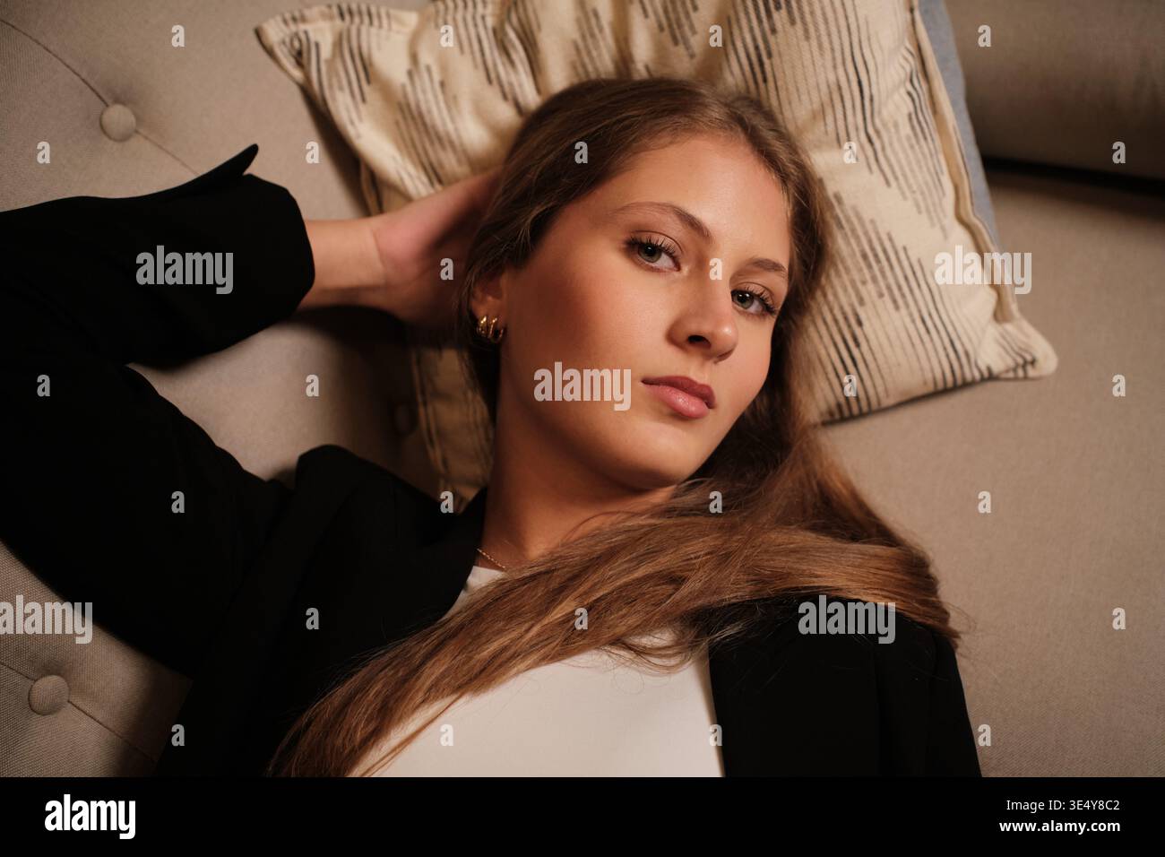Giovane donna che si rilassa sul divano guardando la macchina fotografica Foto Stock