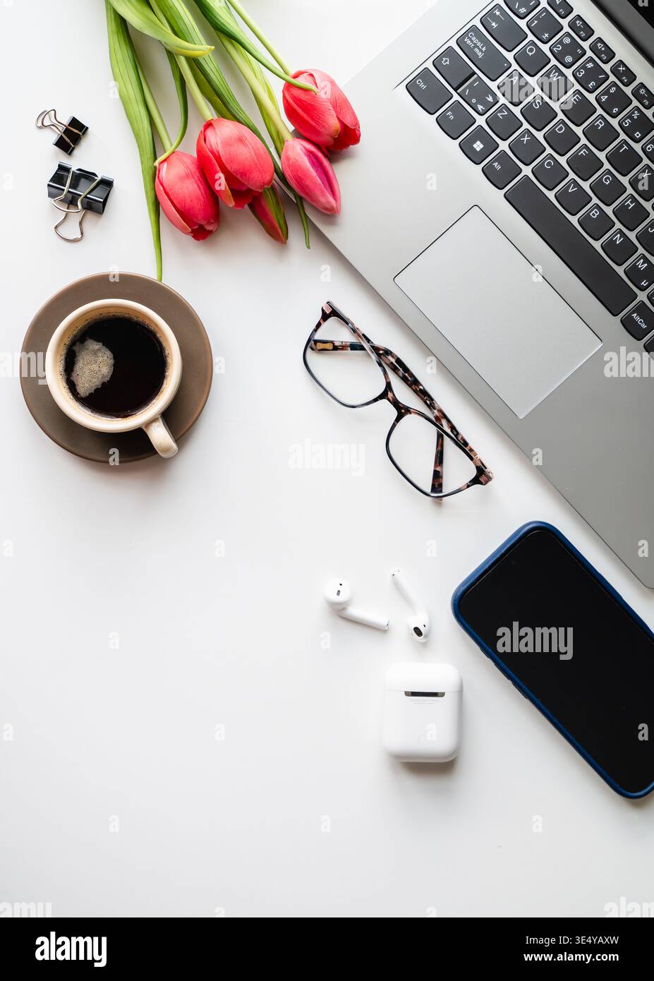 Vista dall'alto del desktop bianco con computer, telefono, caffè e auricolari. Foto Stock