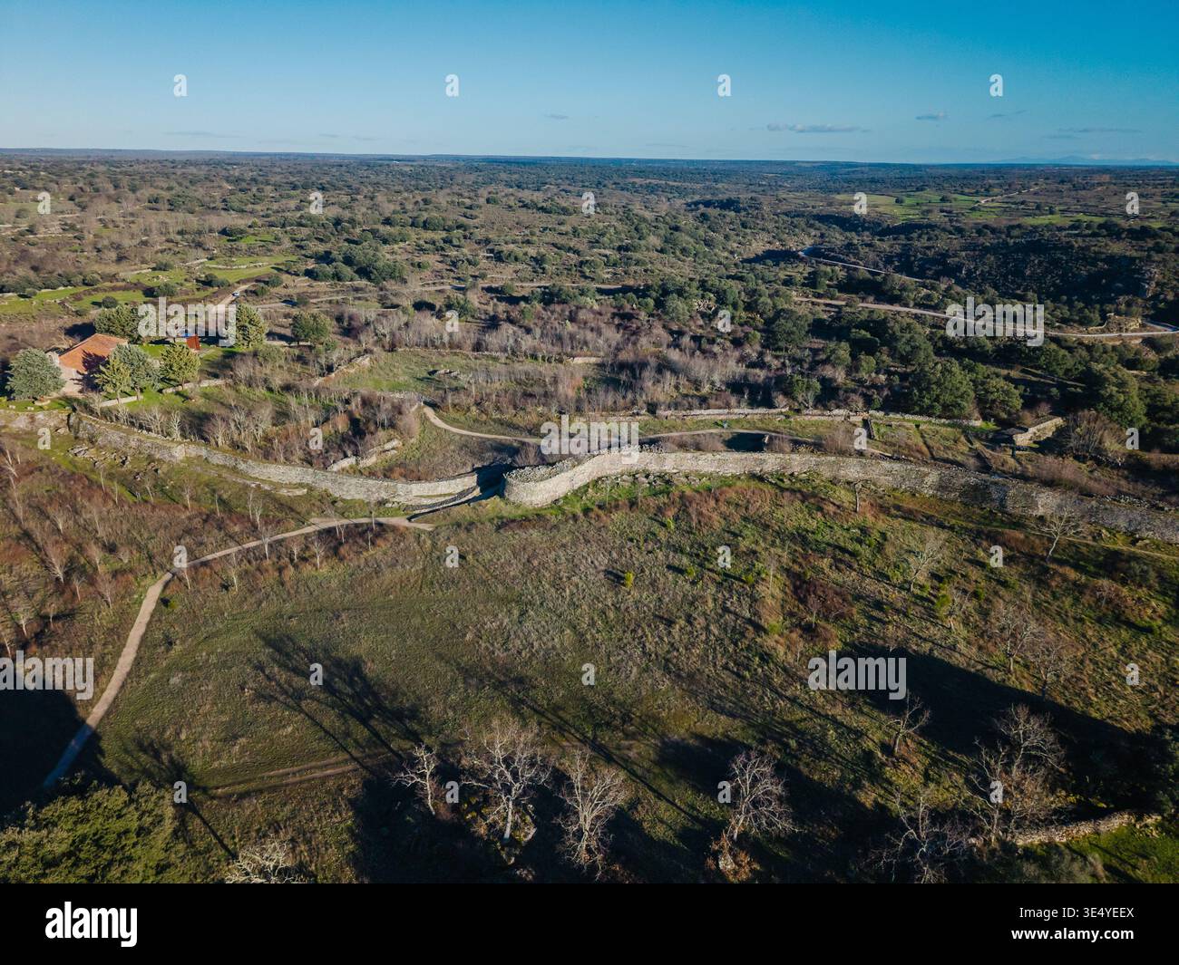 Yecla la Vieja, Veton castro con tortuose mura difensive a secco e rovine sparse tra verdi e aride colline sotto un cielo azzurro e cristallino, vista aerea Foto Stock