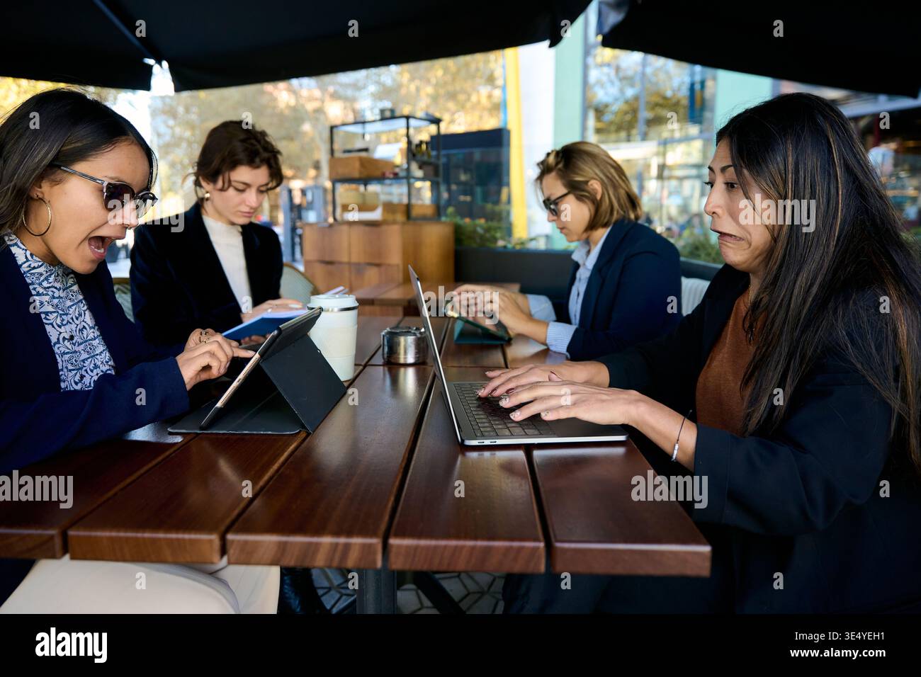 Donne d'affari che reagiscono a notizie sorprendenti sui dispositivi digitali Foto Stock