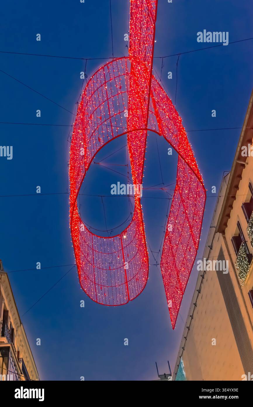 Vista verticale delle luci rosse di Natale che illuminano il cielo serale di Madrid durante le festività del 2021, Spagna. Le decorazioni brillanti Foto Stock