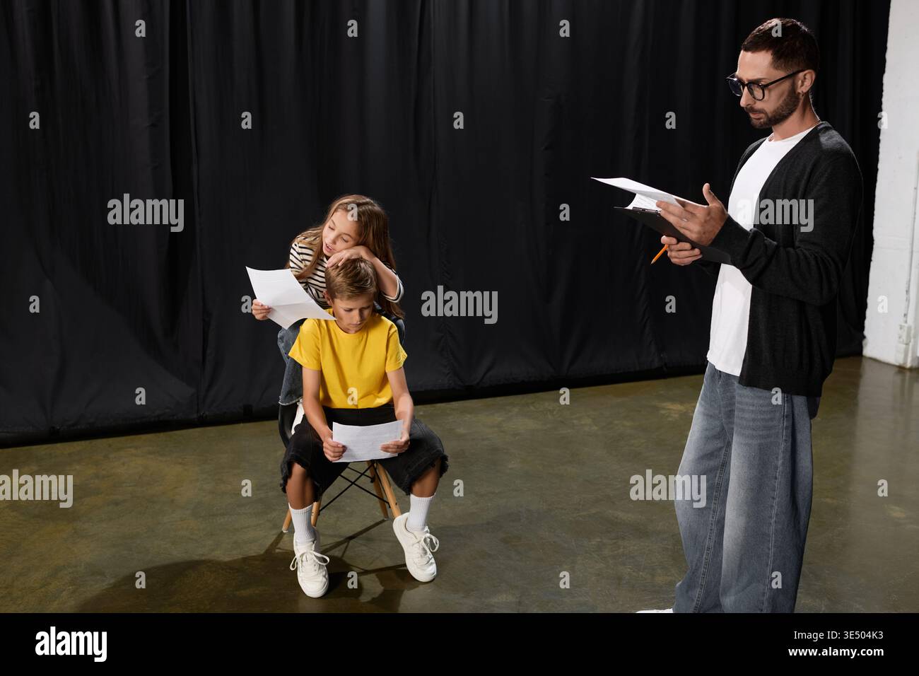 Un tutor elegante ispira i bambini con lezioni di teatro creative e gioie espressioni di gioco. Foto Stock