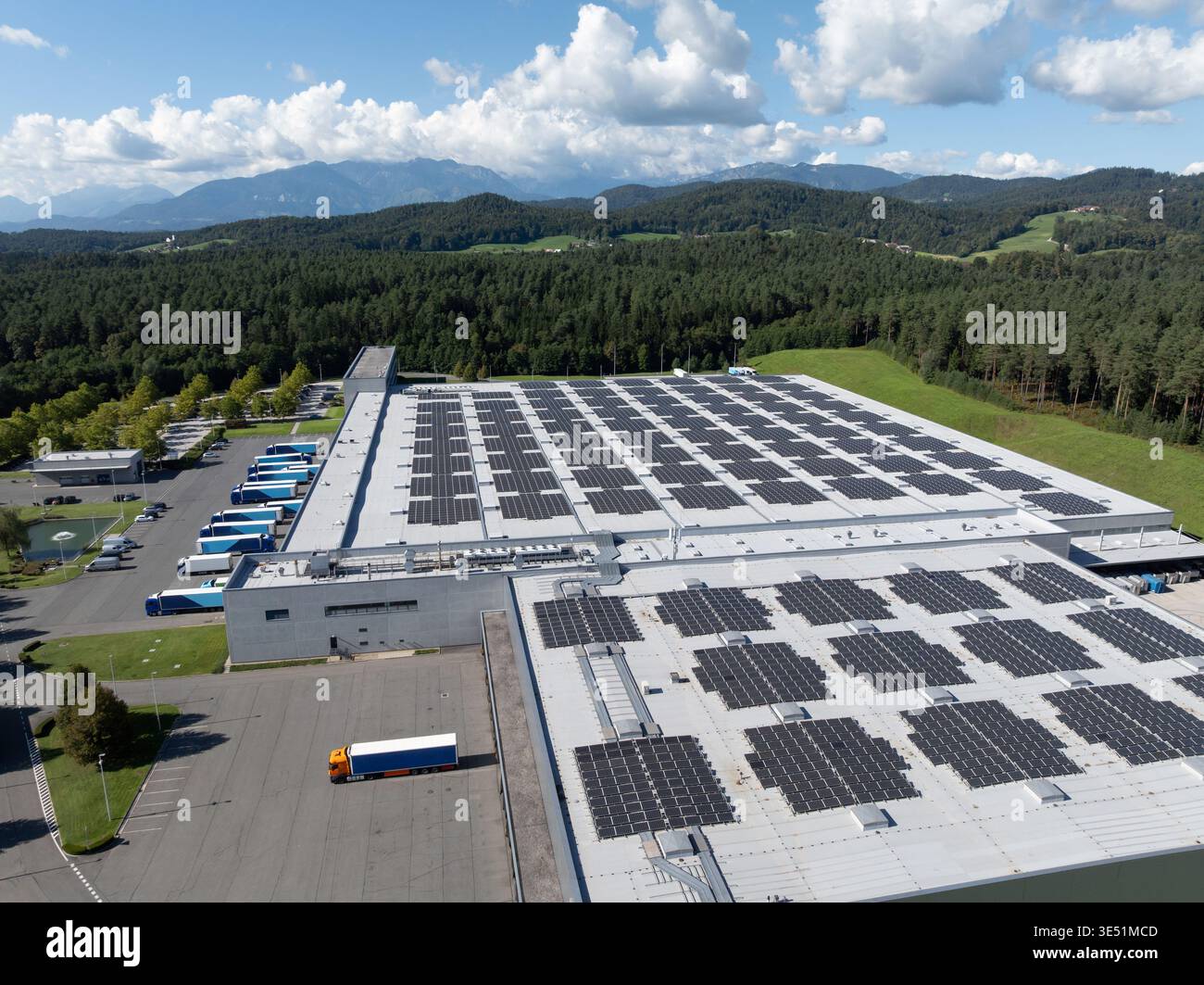 Questa vista aerea mostra un centro logistico con magazzini e camion. La struttura include pannelli solari sul tetto. Foto Stock