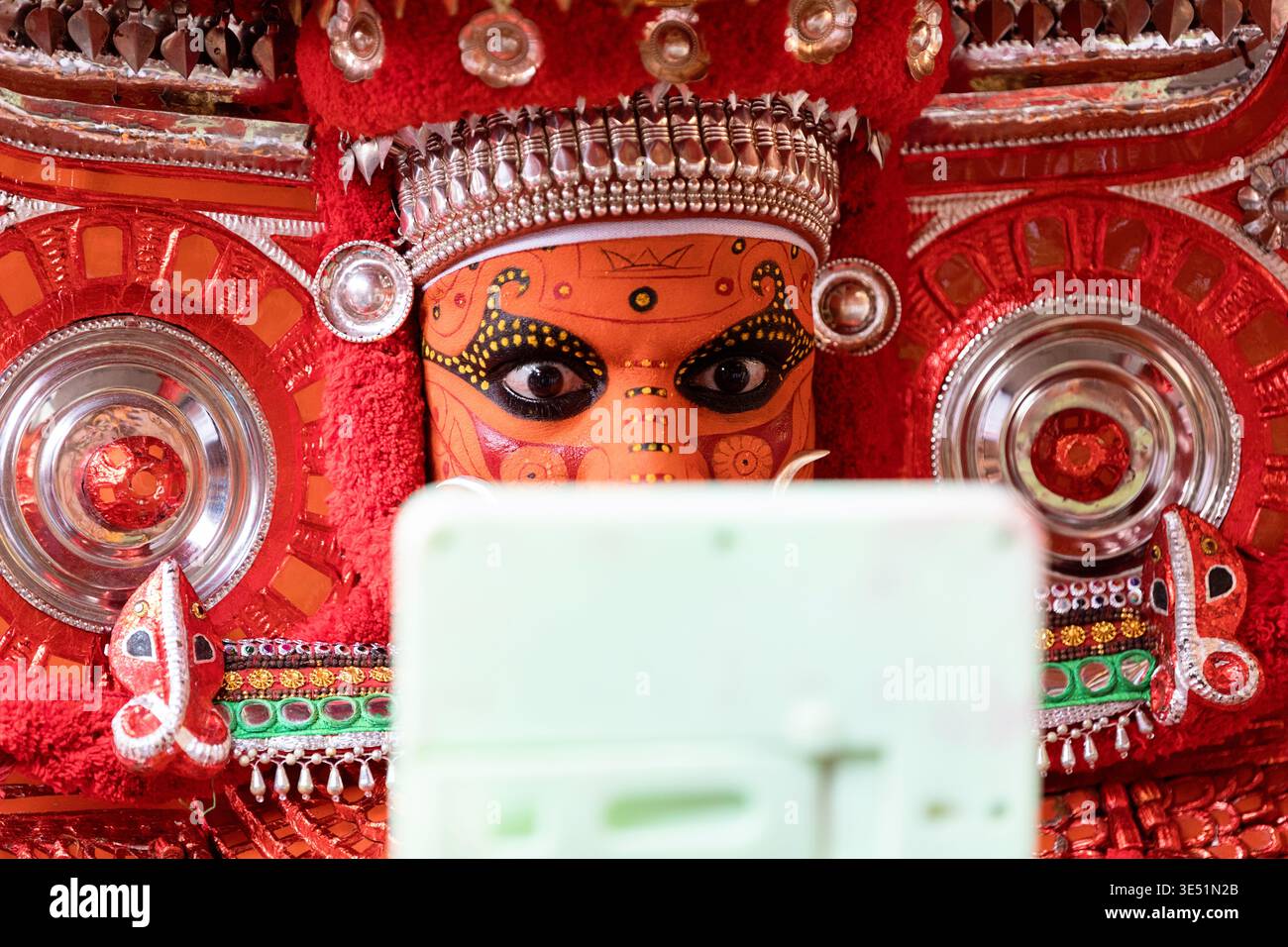 Quando Theyyam interprete rituale di danza in costume tradizionale ornato guarda nello specchio, diventa dio. Kannur Kerala, India Foto Stock