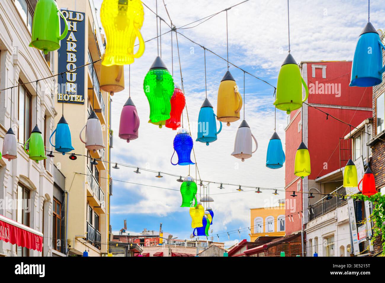 Le colorate lanterne a forma di teiera sono appese sopra una vivace strada di caffetterie e negozi nel quartiere Kumkapi di Istanbul, Turchia. Foto Stock