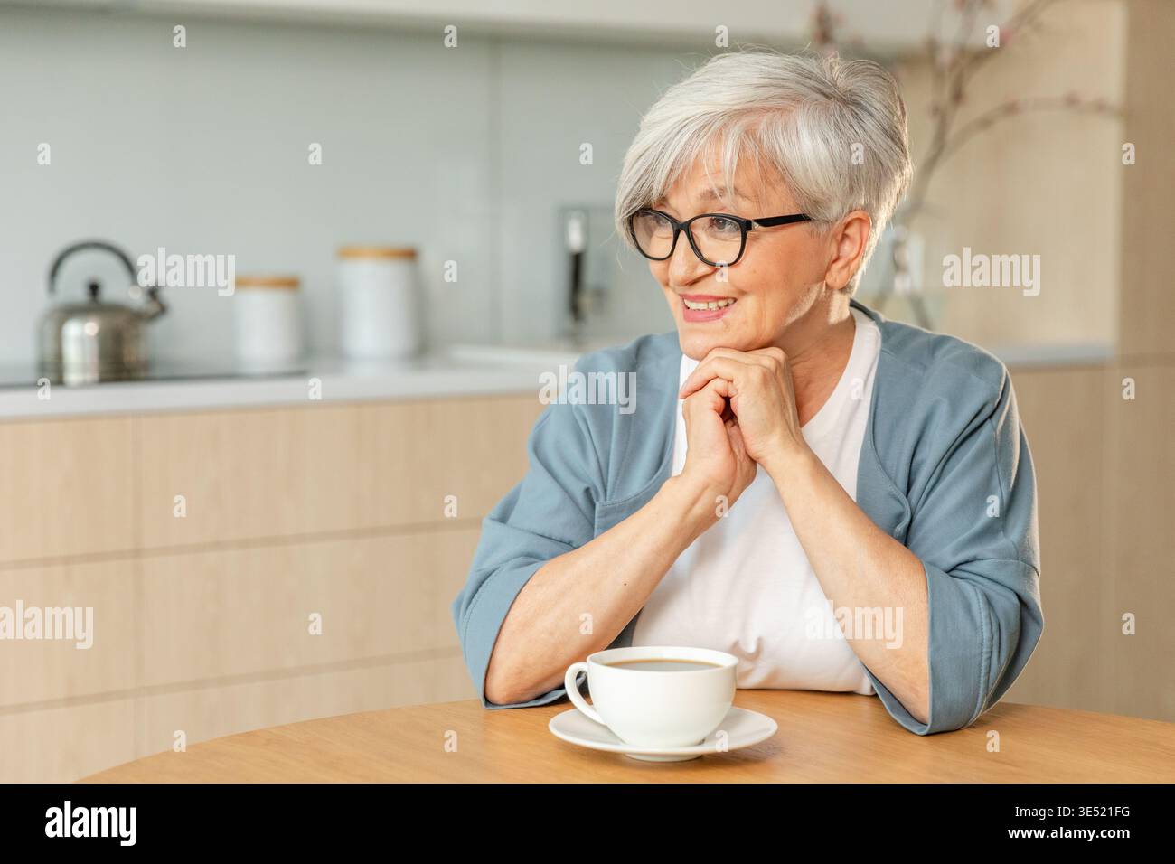 Buon giorno. Comfort rilassato anziano anziano anziano anziano donna nonna che beve bevande calde tè e caffè in cucina a casa. Donna matura che riposa goditi la calma mattinata nella casa moderna da sola. Concetto di pensione Foto Stock