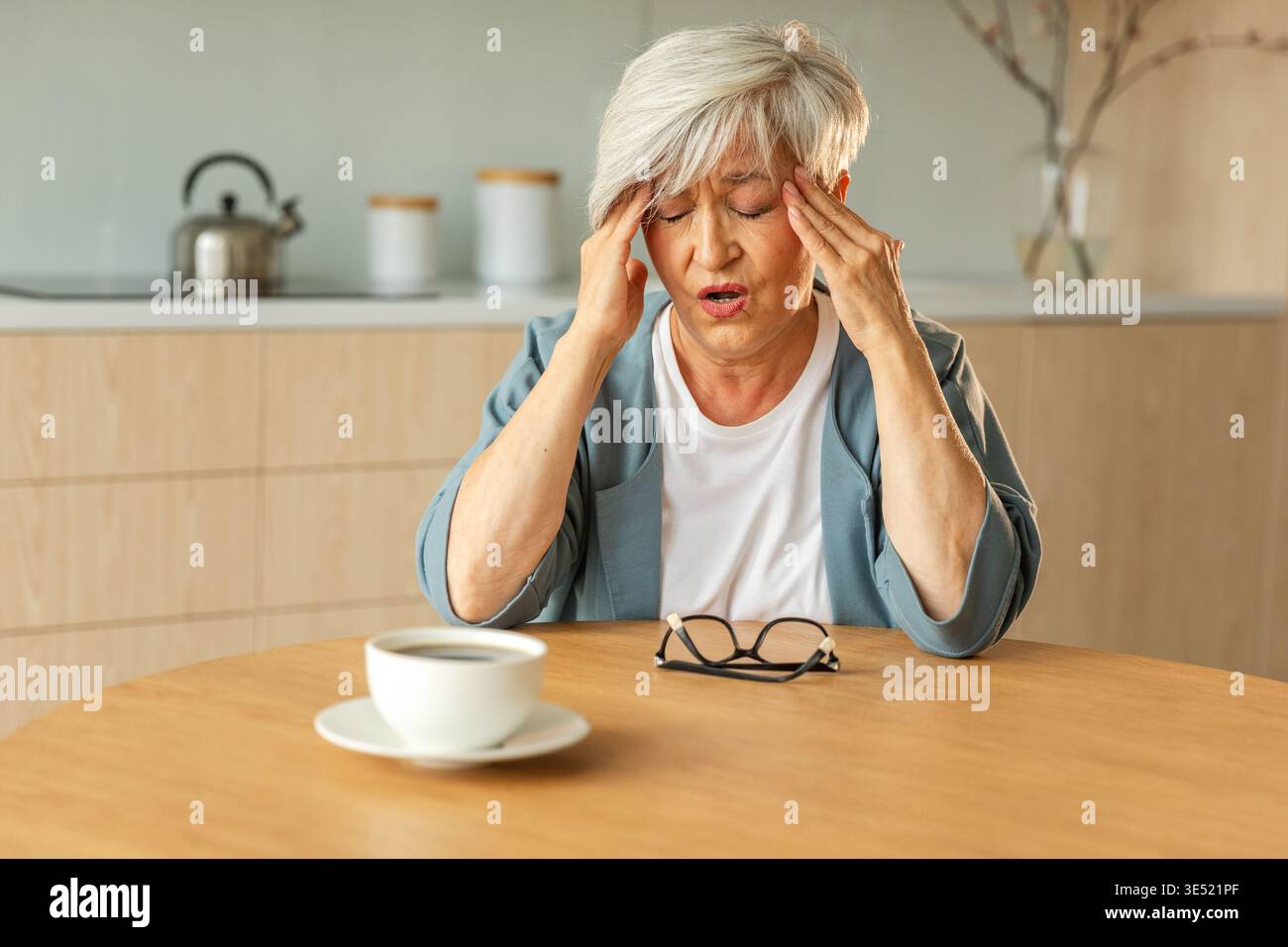 Mal di testa. Donna anziana infelice di mezza età che soffre di mal di testa malata che sfrega le tempie a casa. Anziana nonna anziana matura che tocca i templi che sperimenta stress donna che sente dolore alla testa Foto Stock