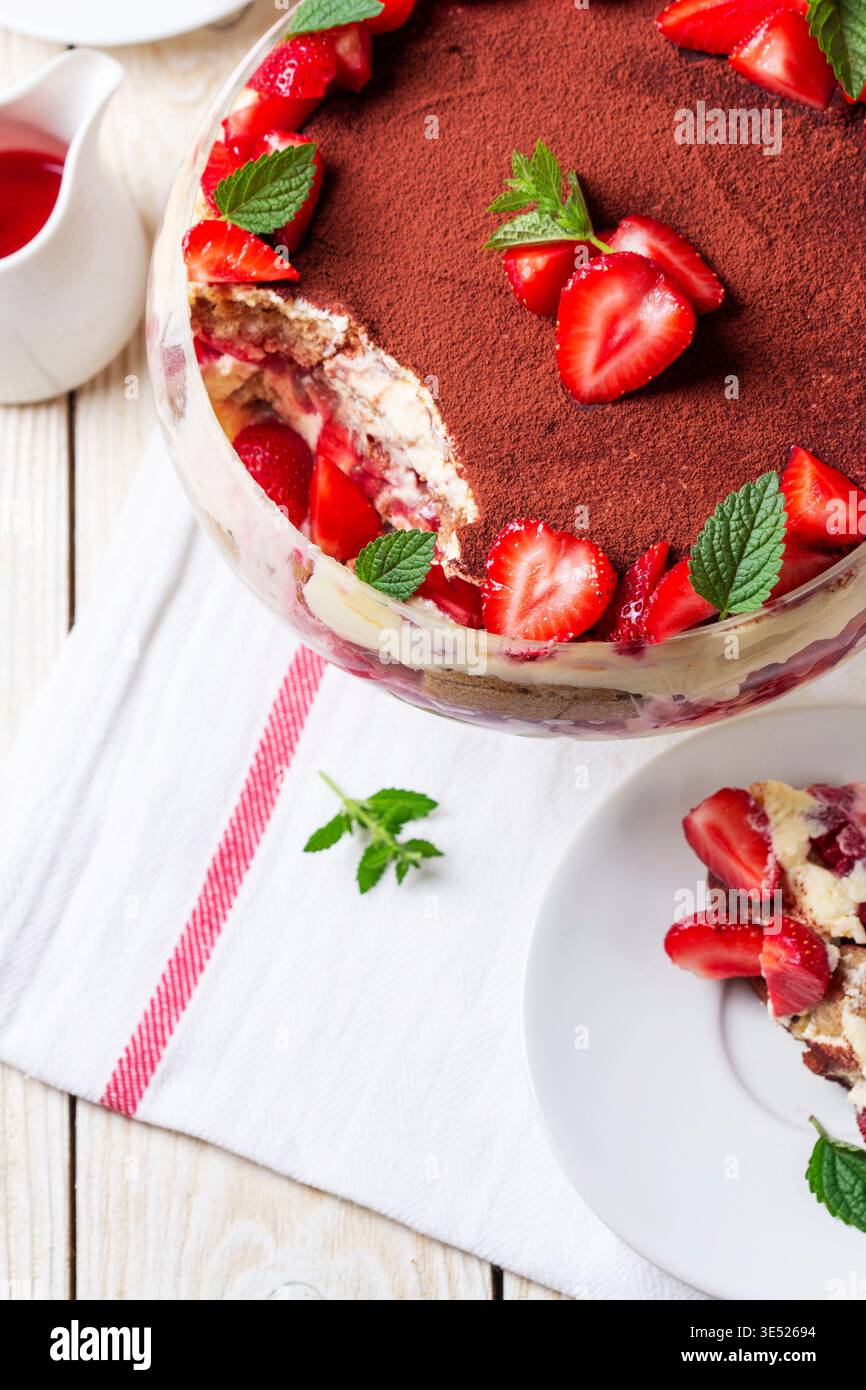 Dessert trifle alla fragola con strati di crema e menta in ciotola di vetro Foto Stock