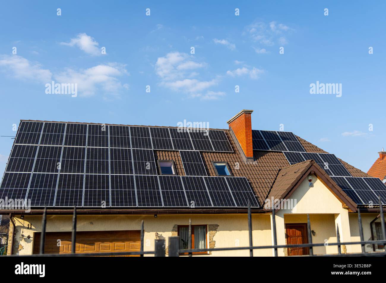 Tetto moderno coperto da pannelli solari. Casa residenziale con pannelli solari sul tetto sotto un cielo azzurro, che rappresentano energia pulita, bollette più basse Foto Stock