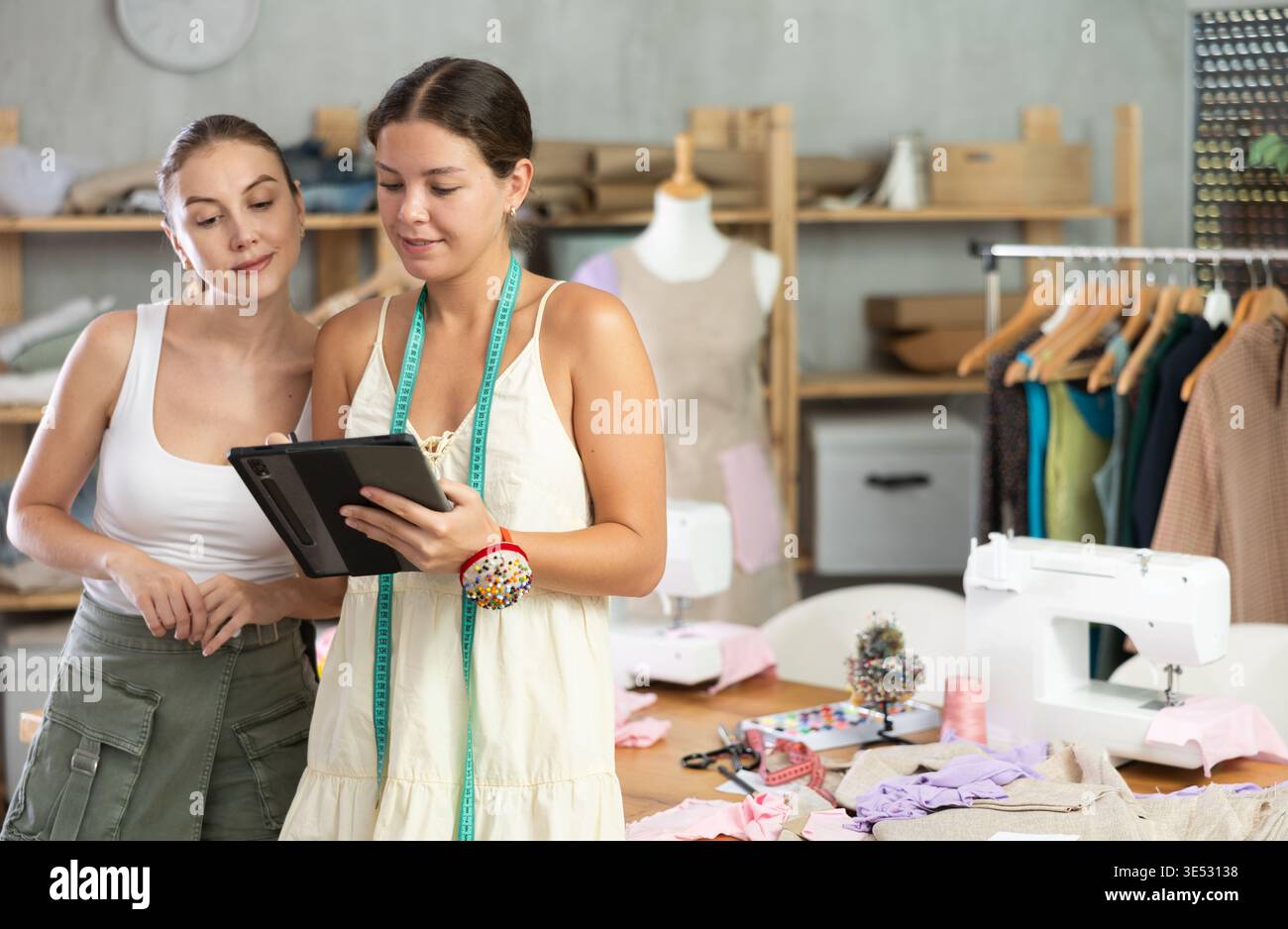 Due sarte che disegnano un modello di vestiti su un tablet Foto Stock