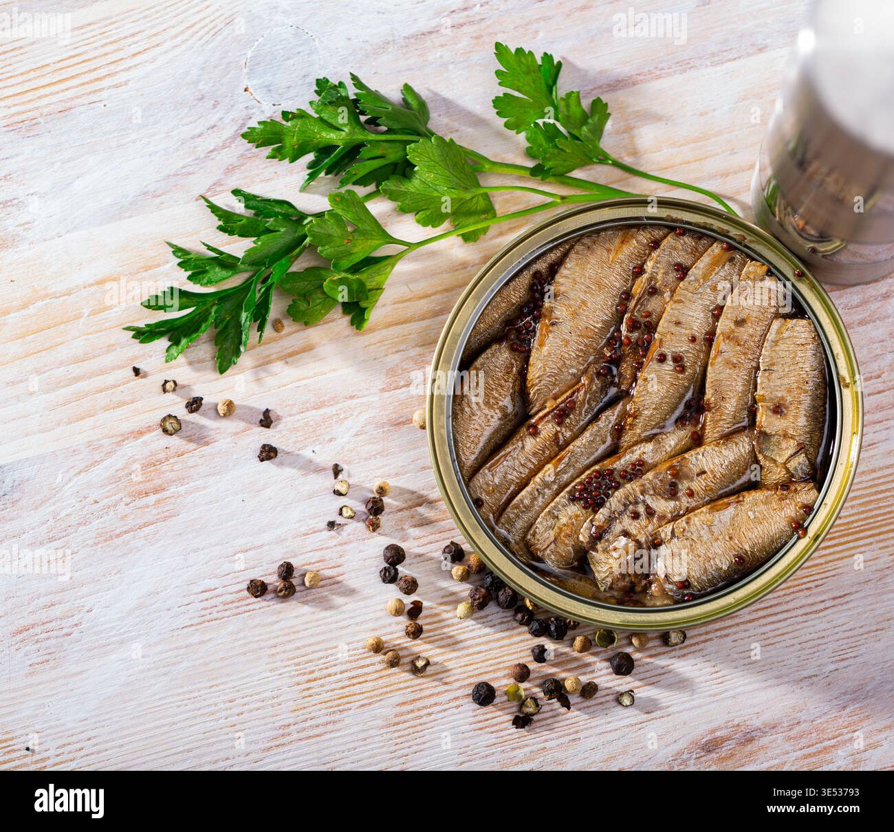 Piccole sardine affumicate sullo sfondo con verdi e pepe nero Foto Stock
