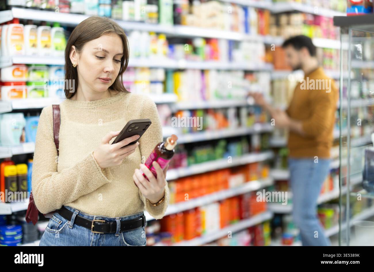 Donna familiarizzare con un buon prodotto, scansionare il codice QR, prendere l'etichetta di lettura utilizzando la fotocamera del telefono in negozio Foto Stock