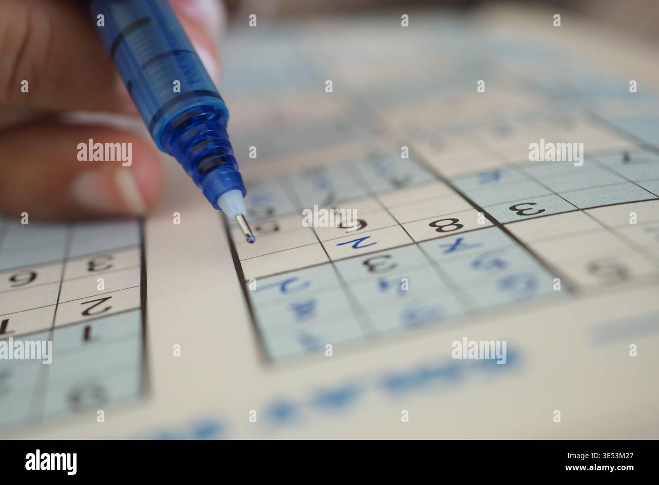 Puzzle Sudoku risolto con una penna blu in primo piano Foto Stock
