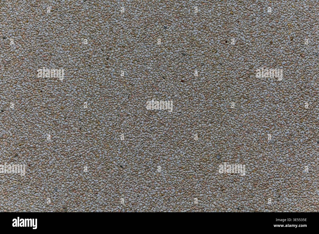 Primo piano di piccoli ciottoli leggeri incorporati nella superficie per creare una texture granulare uniforme. Foto Stock