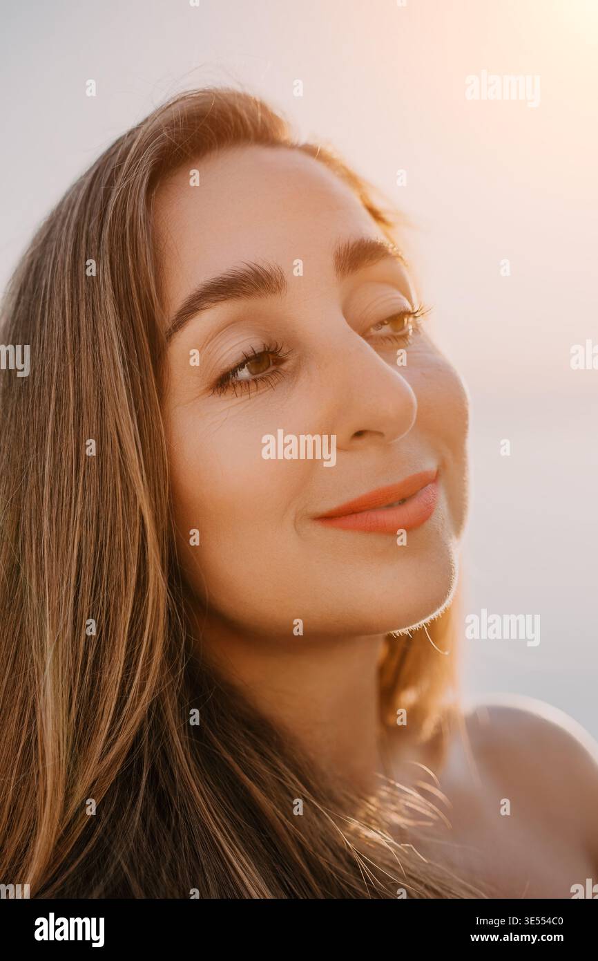 Ritratto di donna al tramonto con una giovane donna che sorride dolcemente durante l'ora d'oro in un tranquillo ambiente all'aperto Foto Stock